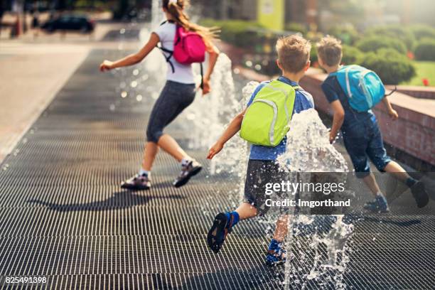 kids running between fountains on a way from school - poland people stock pictures, royalty-free photos & images