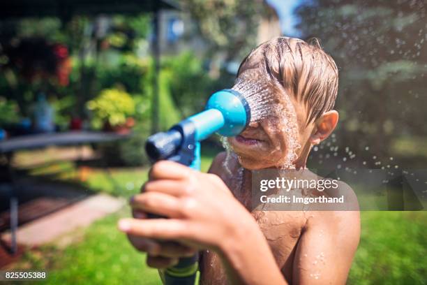 little boy cooling himself with a garden hose - hose stock pictures, royalty-free photos & images