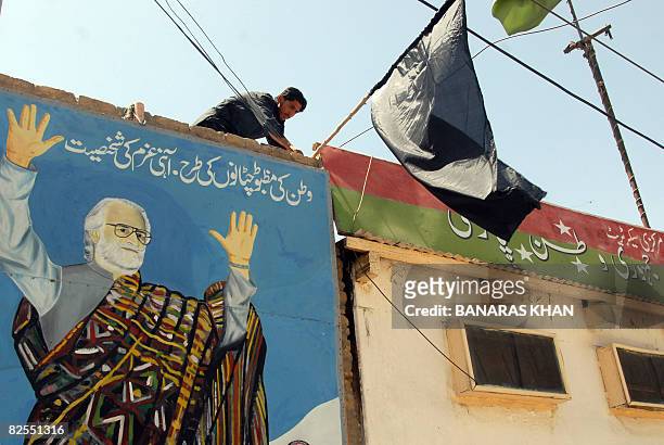 Pakistani man installs a black flag on the top of picture of late tribal chieftain Nawab Akbar Bugti in Quetta on August 26, 2008 on the second...