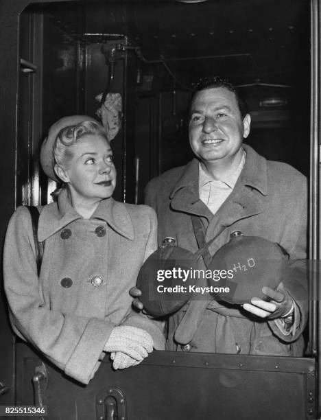 American actor and comedian Phil Harris and his wife, actress Alice Faye arrive at Grand Central Station in New York, armed with bottles of water in...