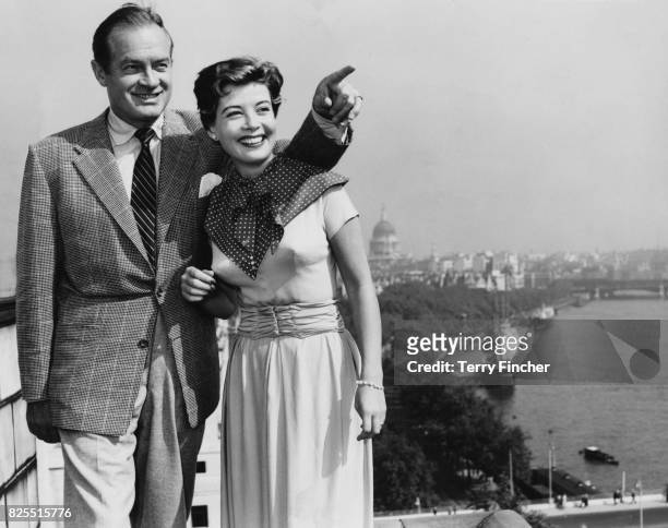 American comedian Bob Hope takes in the London skyline from the roof of the Savoy Hotel, with actress Gloria DeHaven, 8th September 1953. They are...