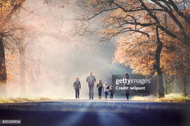 family running together between autumn trees - runner sunrise stock pictures, royalty-free photos & images