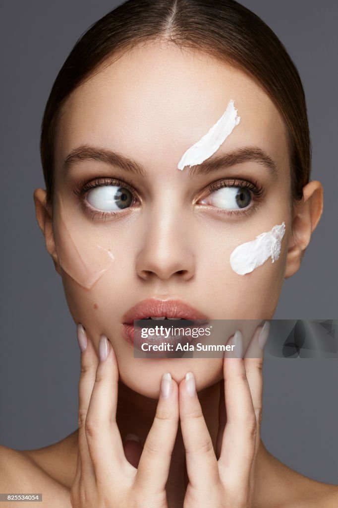 Beauty shot of a young woman with lotion on her cheek