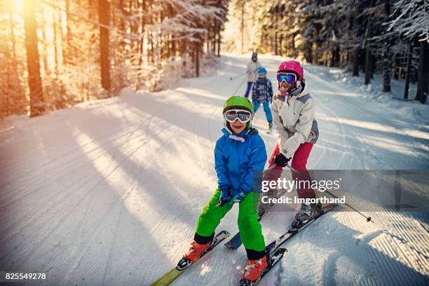 family having fun skiing together on winter day - kids playing in snow imagens e fotografias de stock