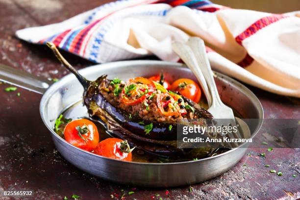 baked aubergine or eggplant stuffed with minced pork and beef, carrot, pepper, cherry tomatoes in a pan on a wooden table, selective focus - eggplant imagens e fotografias de stock