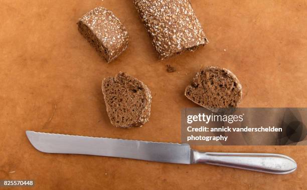 bread knife and cut baguette with pumpkin and sunflower pits. - bread knife stock-fotos und bilder