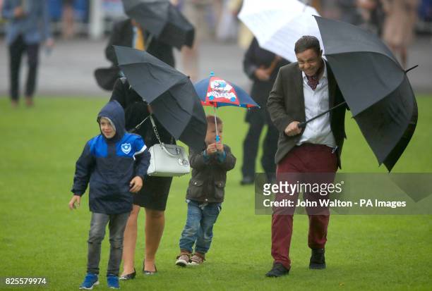 Racegoers in the rain during day two of the Qatar Goodwood Festival at Goodwood Racecourse.