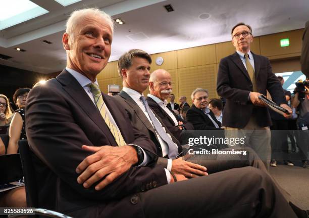 Matthias Mueller, chief executive officer of Volkswagen AG , left, reacts as he sits beside Harald Krueger, chief executive officer of Bayerische...