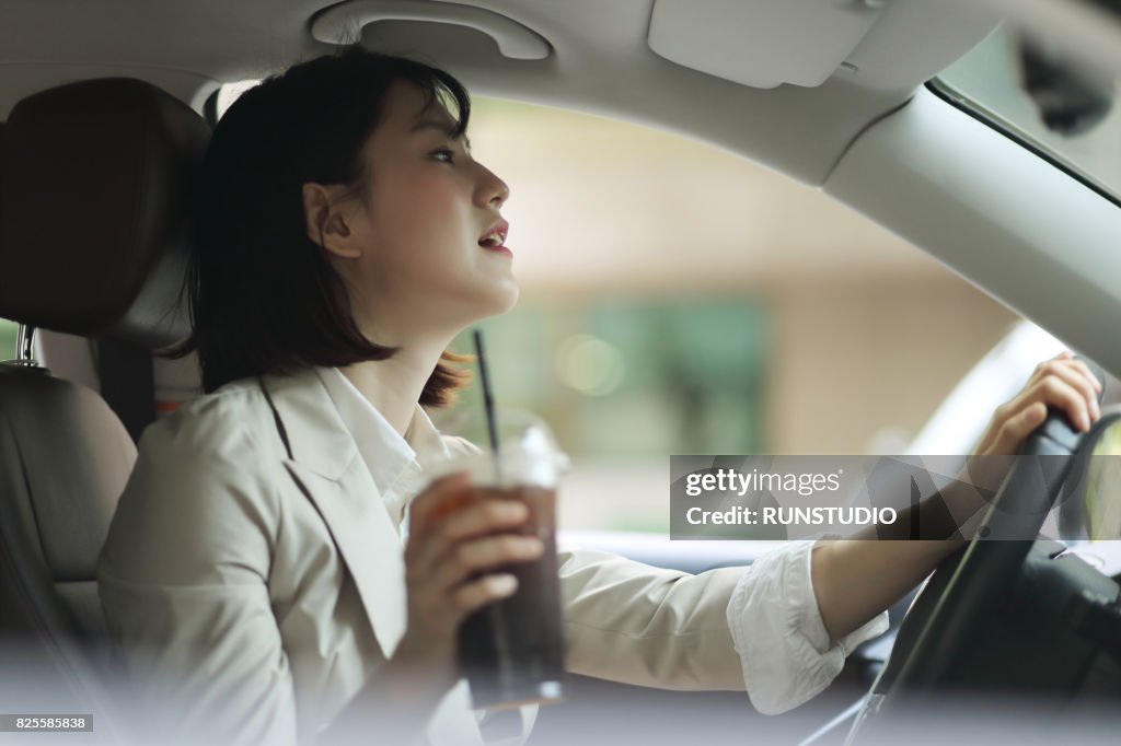 Business woman driving with ice coffee