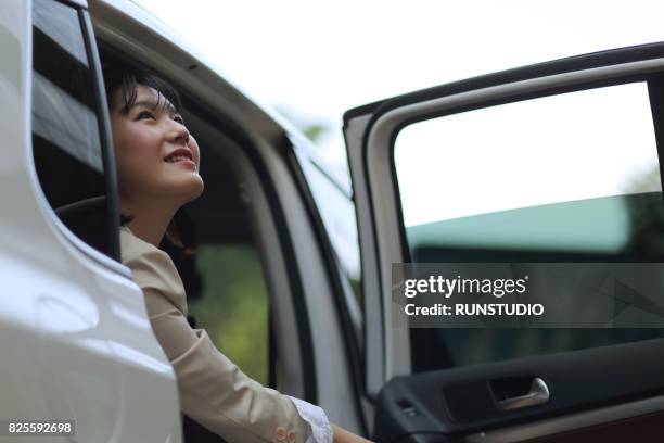 business woman opening the rear seat door of the car looking at the sky - open sky stockfoto's en -beelden