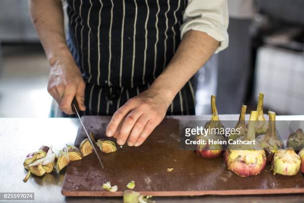 chef preparing artichokes on chopping board in italian restaurant - east london fotografías e imágenes de stock
