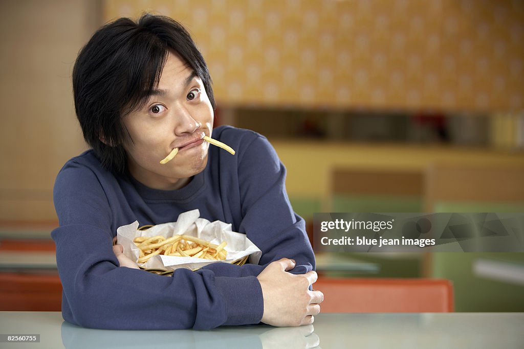 A young man enjoying his fries.