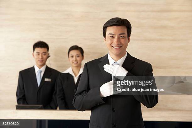 portrait of a concierge and team. - adjusting blue tie stock-fotos und bilder