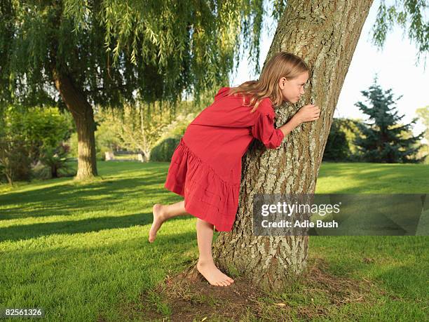 young girl hiding behind tree - girl hiding behind bush stock pictures, royalty-free photos & images