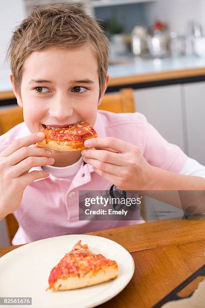 boy eating a piece of pizza - 男の子だけ ストックフォトと画像