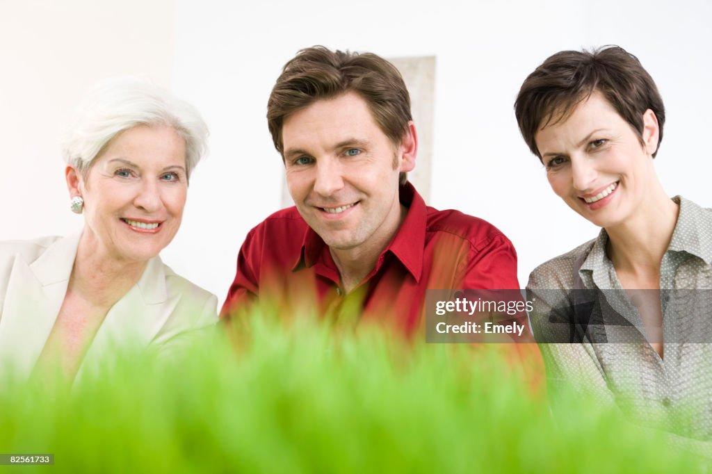 Man and two women in front of grass