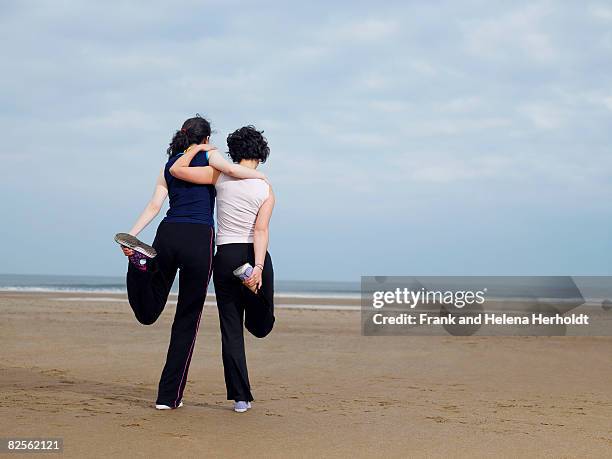 two young females stretching on beach - croyde beach stock pictures, royalty-free photos & images
