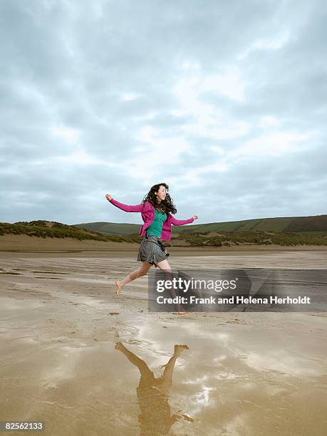 young female jumping on beach - croyde beach stock pictures, royalty-free photos & images