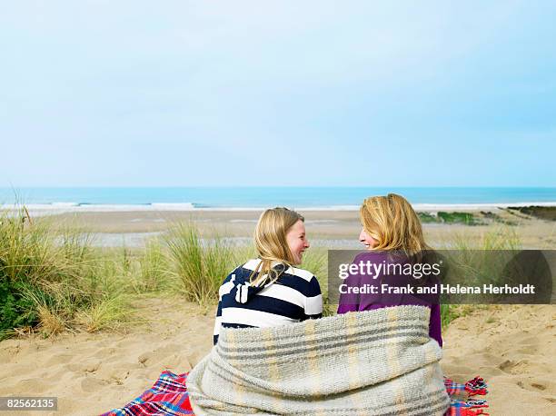 girls sitting on sand dune with blanket - croyde beach stock pictures, royalty-free photos & images
