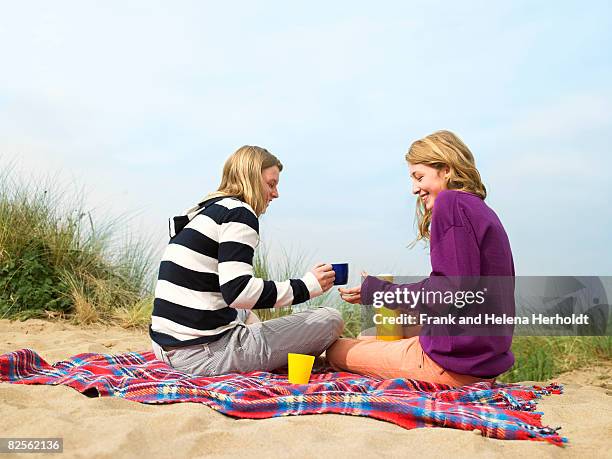 women drinking hot drink, on blanket - croyde beach stock pictures, royalty-free photos & images