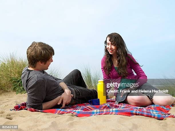 couple lying on blanket on sand dune - croyde beach stock pictures, royalty-free photos & images