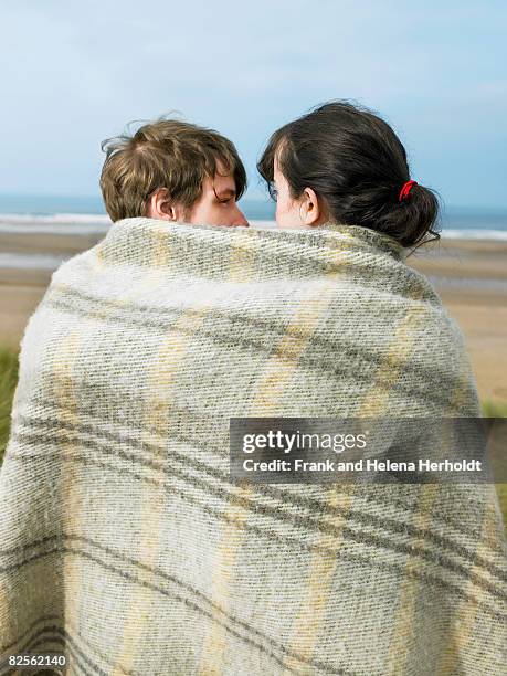 young couple wrapped in blanket - croyde beach stock pictures, royalty-free photos & images