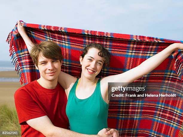 man hugging woman holding blanket - croyde beach stock pictures, royalty-free photos & images