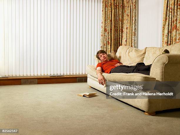 man sleeping on sofa - croyde stock-fotos und bilder