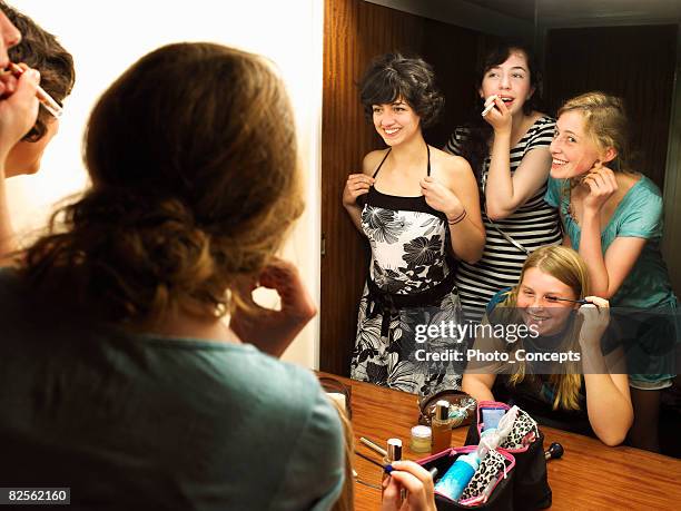 females putting on make-up by mirror - aankleden stockfoto's en -beelden
