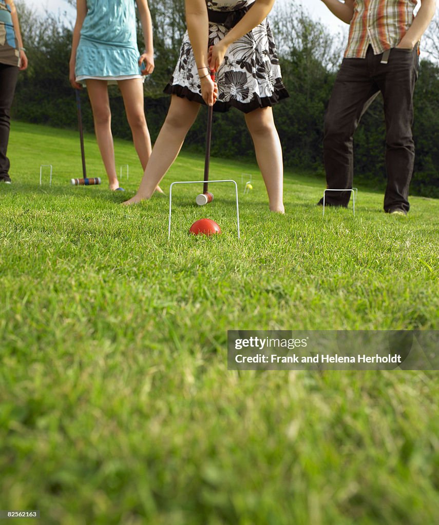 Man and women playing croquet in garden