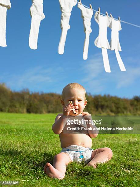 baby sitting and holding clothes peg. - croyde stock pictures, royalty-free photos & images