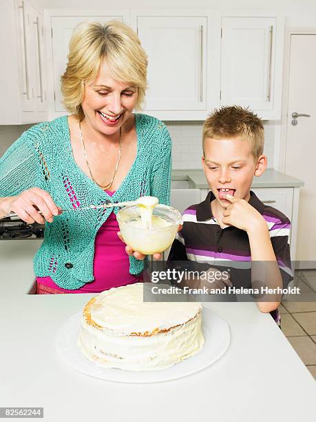 senior woman and boy decorating cake - woman lick knife stock pictures, royalty-free photos & images
