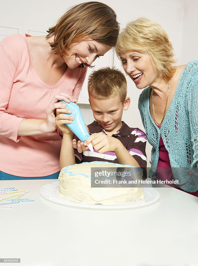 Grandmother, boy and mom decorating cake