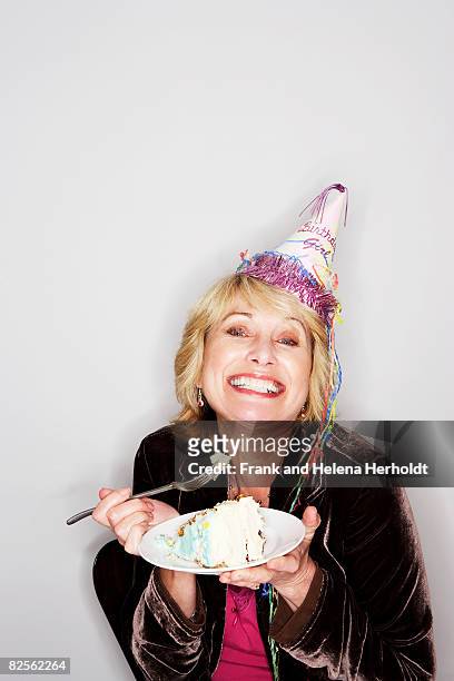 senior woman eating birthday cake - party hat stock pictures, royalty-free photos & images