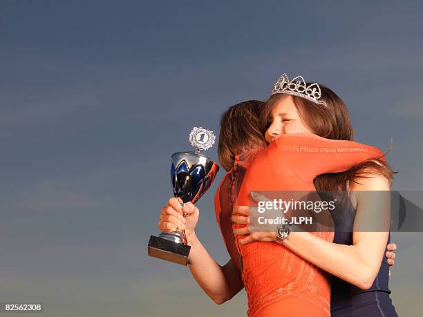 woman hugging woman, holding trophy - beauty contest photos et images de collection