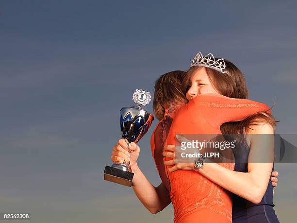 woman hugging woman, holding trophy - beauty contest stockfoto's en -beelden