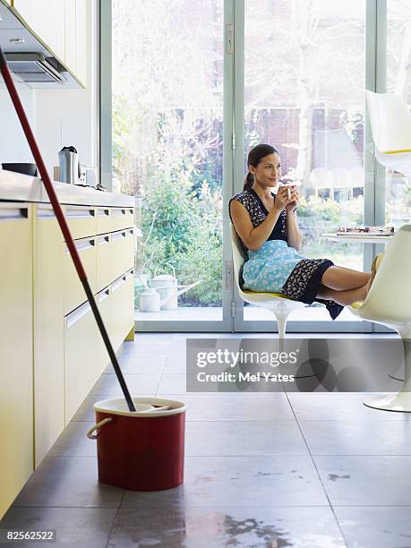 young woman relaxing, mop in foreground - daily bucket photos et images de collection