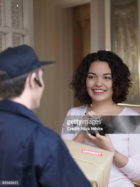 woman signing for package with courier - firma digital fotografías e imágenes de stock