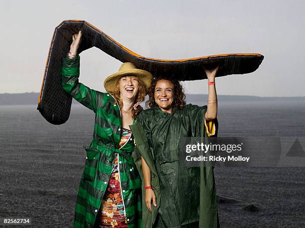 two women taking shelter from the rain - beach shelter stockfoto's en -beelden