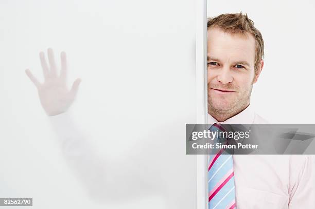 businessman with hand on glass panel - breaking through wall stockfoto's en -beelden