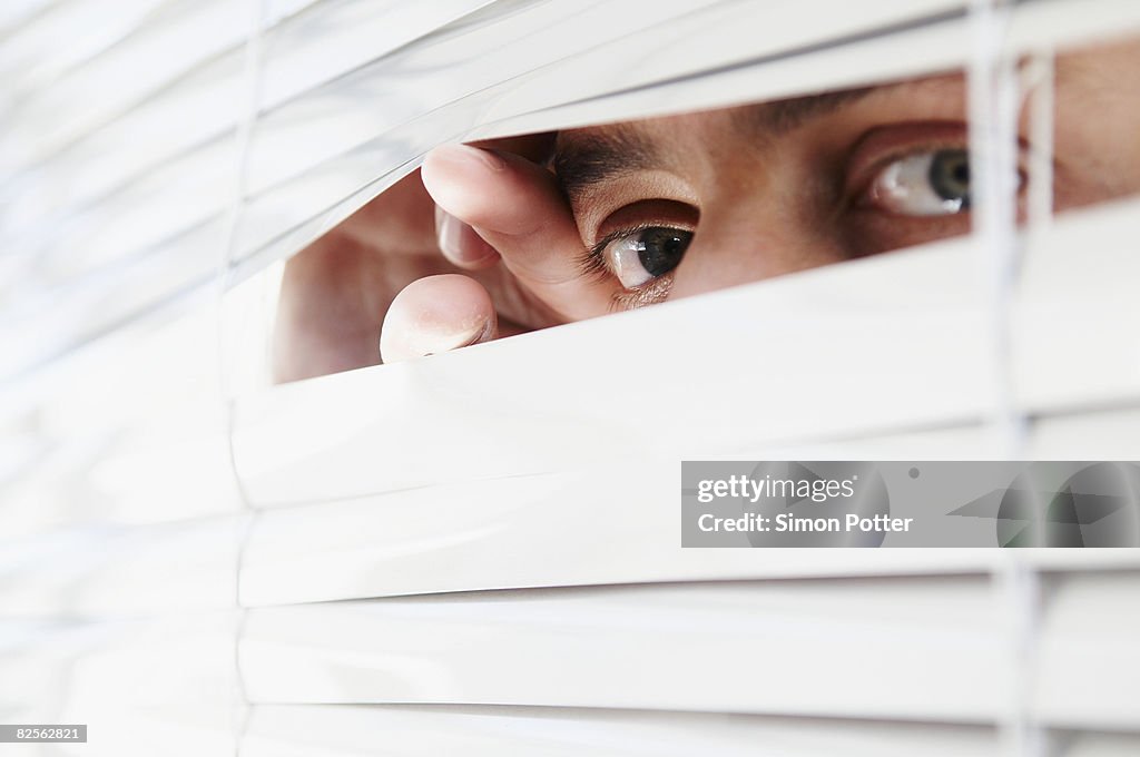 Man looking through office blinds