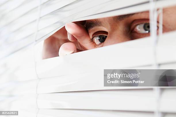 man looking through office blinds - whistle blower stock pictures, royalty-free photos & images