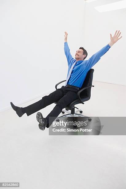 man speeds through office on chair - office chair stock-fotos und bilder