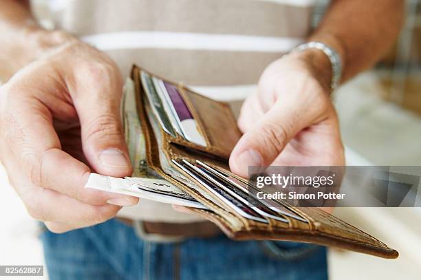man removes cash from wallet - cartera fotografías e imágenes de stock