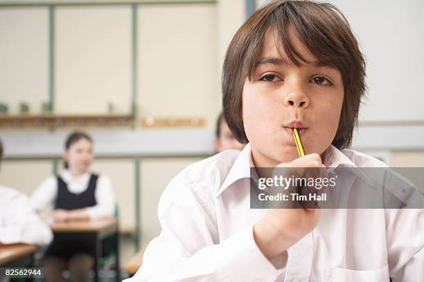 boy with pencil in mouth, in classroom - boy asking stock pictures, royalty-free photos & images