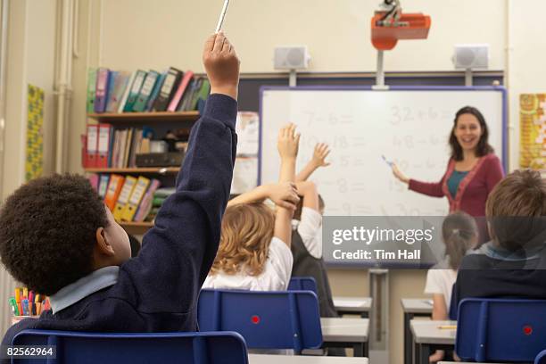 children raising hands in classroom - elementary school stock pictures, royalty-free photos & images