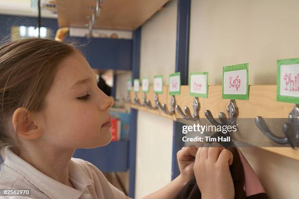 girl hanging her coat in school - garment tag stock pictures, royalty-free photos & images