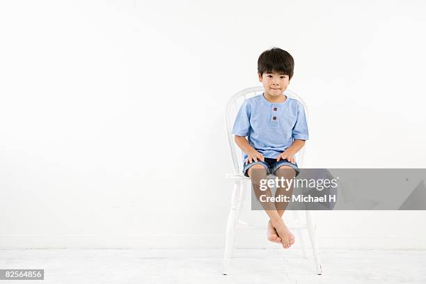 a boy is sitting on white chair in front of wall - michael sit stock pictures, royalty-free photos & images