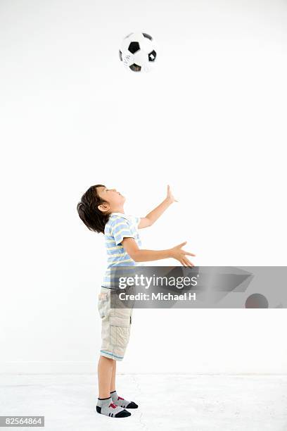 a boy is throwing out the soccer ball up - heading the ball photos et images de collection