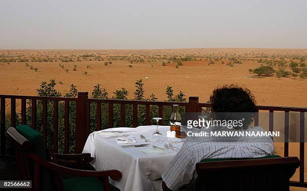 Guest looks at the desert view from the resturant of al-Maha resort and nature reserve, some 100 kms south of the Gulf emirate of Dubai, on June 30,...